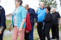 senior citizen fellowship group walking together in a park 
