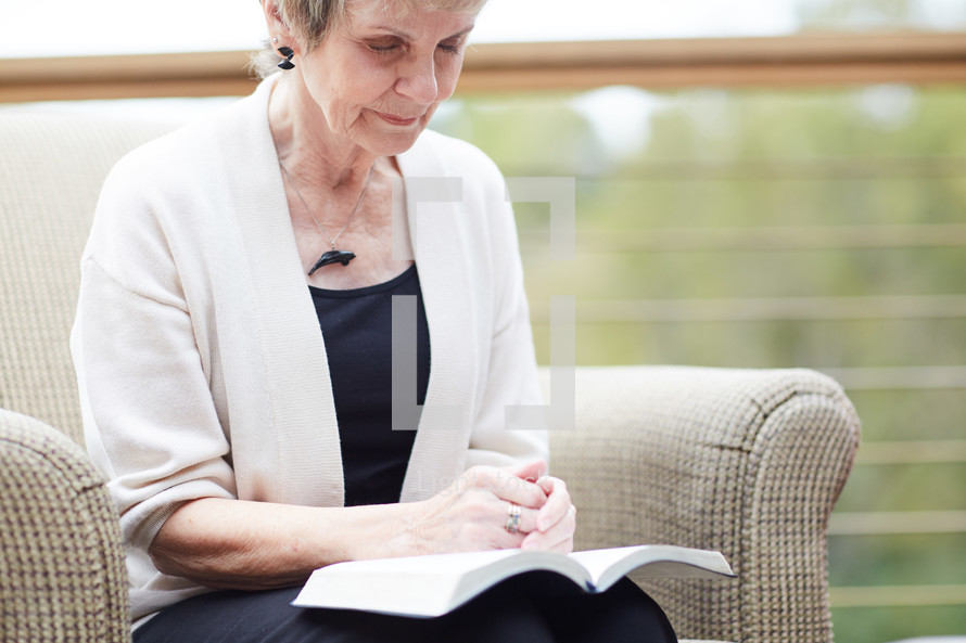 a woman with a Bible in her lap praying 