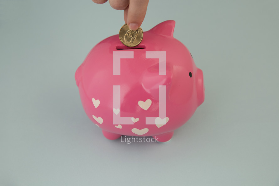 placing a coin in a piggy bank with hearts 
