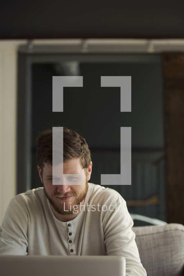 man looking at a computer screen smiling 