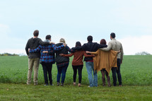 a united group of people standing with arms around each other 