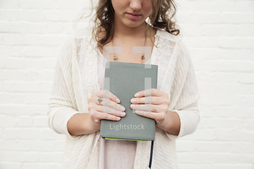 torso of a woman holding a Bible