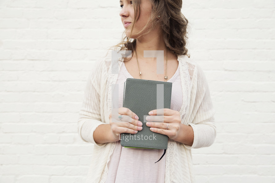 a young woman holding a Bible to her chest 