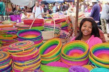 a woman in a market selling colorful baskets 