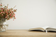 flowers in a vase and open Bible on a table 