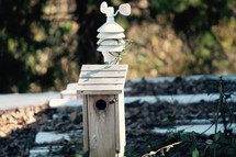 a bird house on a tin roof with a weather vane 