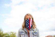 a young woman wearing an American flag bandana around her face 