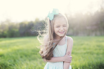 a little girl standing in a field of green grass laughing 