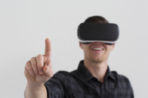 A man wearing 3d virtual reality glasses and holding his finger up.