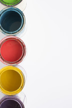 Open cans of colorful paint on a white background.