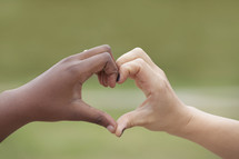 hands from two different races forming a heart shape 