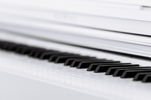 Close side view of shiny black and white piano keys with the reflection of the white edge from low angle with shallow depth of field. selective focus.