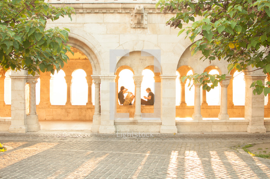people resting under an historic structure 