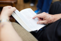 elderly man reading a Bible in his lap 