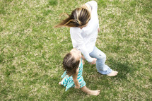 mother and daughter walking holding hands in grass