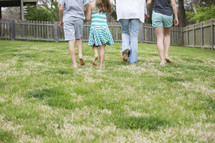 a family walking holding hands in the back yard 