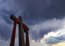 Cross with red banner against sunlit clouds