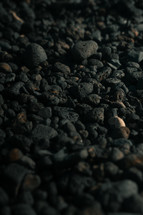 Black volcanic rocks, porous stones on a beach, pebbles,