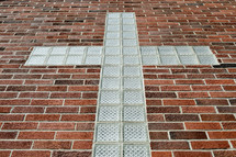 glass block cross against a brick wall 