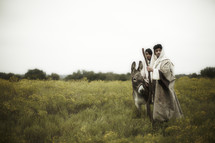 Biblical couple in wilderness riding donkey