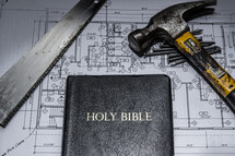 saw, blueprints, and a Bible 