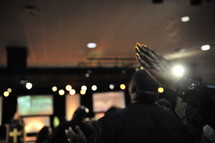 Congregation with hands raised praising God during worship service.