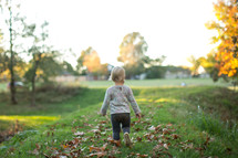 a toddler girl playing outdoors in fall 