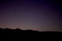 stars in the night sky above a mountain range 