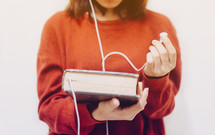 a woman holding a Bible and listening to earbuds 
