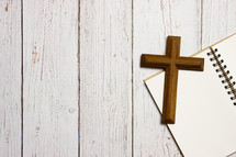 cross and notebook on a wood background 