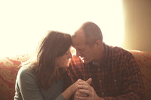 Mature couple praying together in home. 