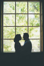 a couple standing in front of a window 