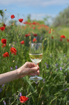 a woman in a field of wild flowers holding up a wine glass 