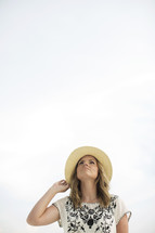 woman in a straw hat looking up to God 