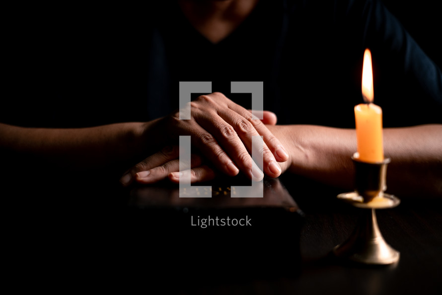 Bible and candlelight with praying hands