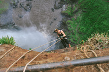 a woman climbing down the side of a cliff 