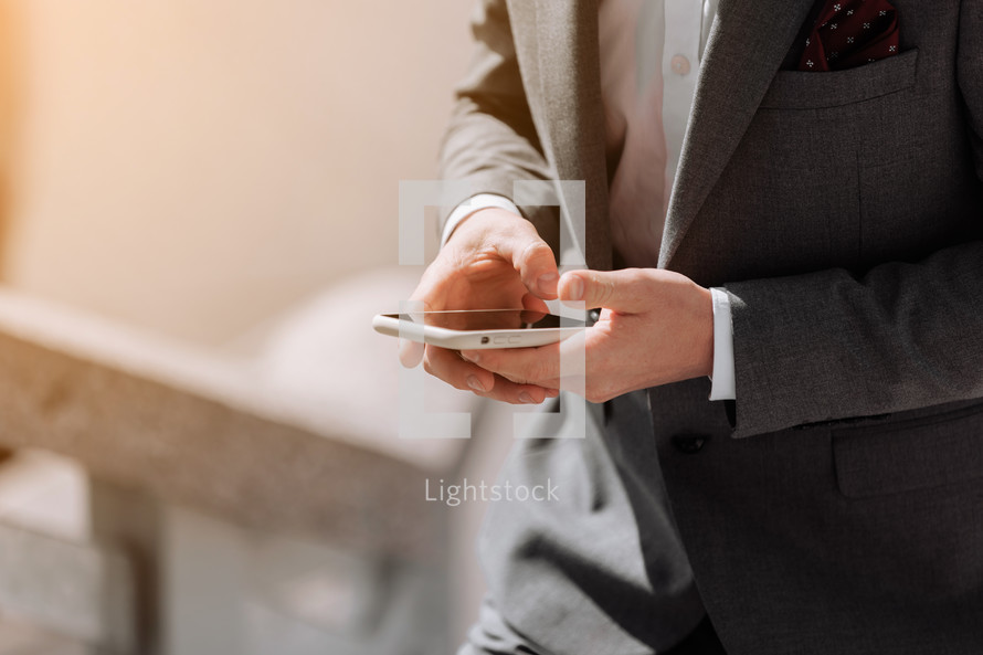 Closeup shot of an unrecognisable businessman in suit is using smartphone outdoors by the office. Making moves in the corporate world. Staying on top of the latest business news. copy space.