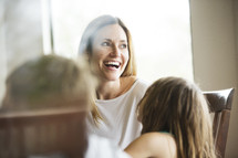 a mother laughing and talking with her kids at a kitchen table 