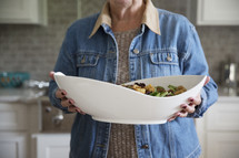 a woman holding a large salad 