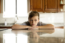 a pouting boy in a kitchen 