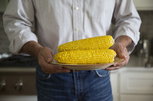 a man holding corn on the cob