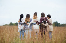 group of women walking through a field holding Bibles