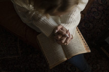 a woman with praying hands over a Bible 