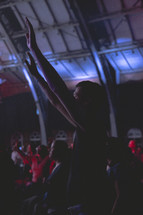 a man standing with raised hands at a worship service 