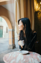 a woman sitting alone at a table with a coffee cup 