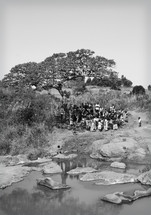 people gathered for a worship service under a tree