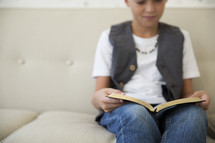 a boy child sitting reading a Bible 