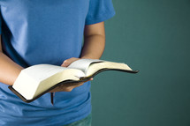 A young person holds her Bible opened to read