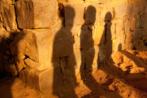shadows of men on a stone wall 