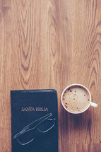 Santa Biblia, reading glasses, and cappuccino